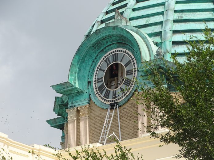 <p></noscript><p><strong>PEEK-A-BOO —</strong> A worker from The Verdin Co., the Cincinnati firm repairing the clock inside the Historic Volusia County Courthouse dome, peeks out of the south-facing clock face, which faces West New York Avenue, on a recent morning.</p></p><p>BEACON PHOTO/ANTHONY DeFEO</p>