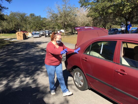 <p><p>WORKING HARD FOR OTHERS — Taking safety precautions that include wearing rubber gloves, Donna Cobb prepares to load food for a household in need. Cobb was one of approximately 30 volunteers at the event.</p></p><p></p>